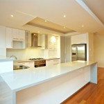 Modern White Kitchen Bench, rangehood, stove and cupboards with polished floor boards in a custom build dual occupancy home