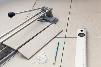 Grey floor tiles with cutting instrument, measure and pencil.