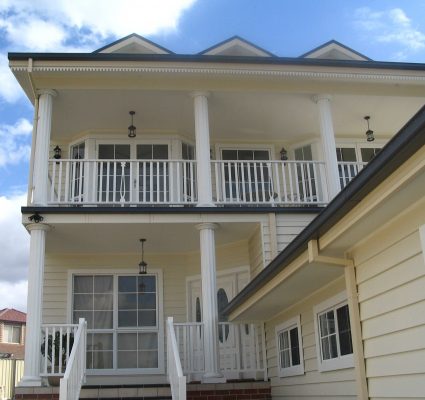 Traditional 3 Storey Home with cream weatherboard, stairs on left and balcony above
