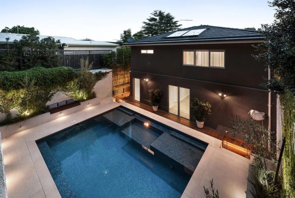 large outdoor swimming pool at back of custom build double storey home