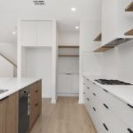 Modern white kitchen with wood accesnts and butler's pantry entrance in the distance