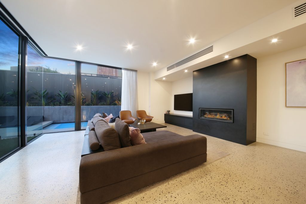 Custom home with outdoor swimming pool, ceiling to floor windows, polished cut concrete floors, gas log heater, modern downlights and modular lounge.